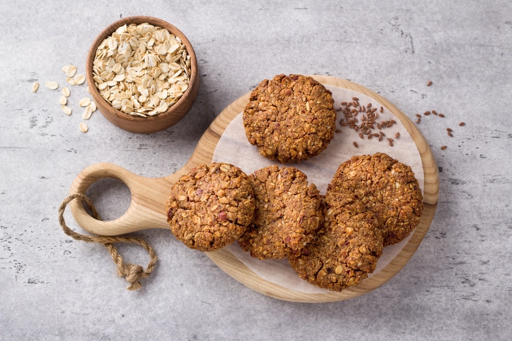Healthy oatmeal cookies with dates, nuts and flaxseed on a wooden board on a gray textured background, top view. Delicious homemade vegan food